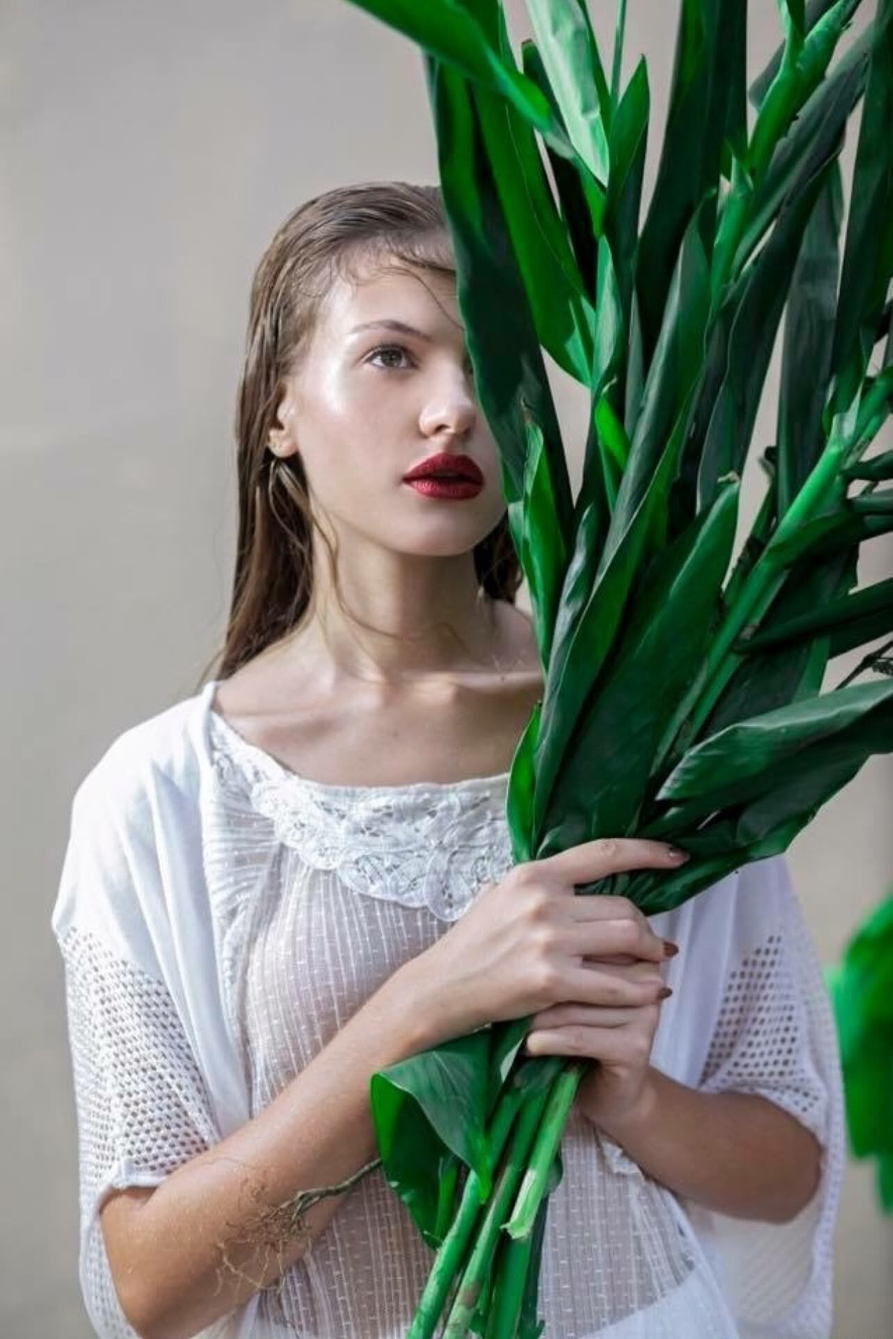 Editorial de moda com folhas verdes e maquilhagem artística